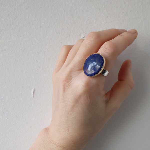 lapis lazuli gemstone ring set in gold with a sterling silver ring - on index finger in light