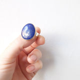 lapis lazuli gemstone ring set in gold with a sterling silver ring - on thumb in good light