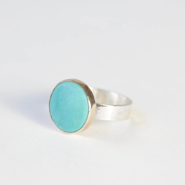bright small turquoise gemstone ring set in 9ct gold with silver ring - front left